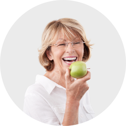 femme agée avec de belles dents croque une pomme 