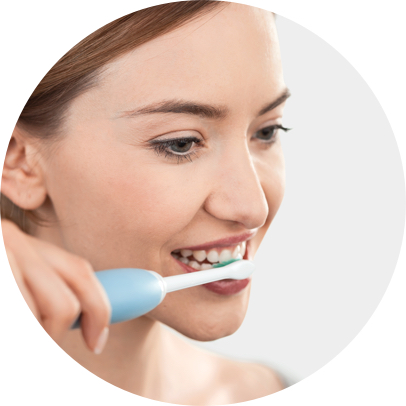 femme se brosse les dents avec une brosse à dent électrique